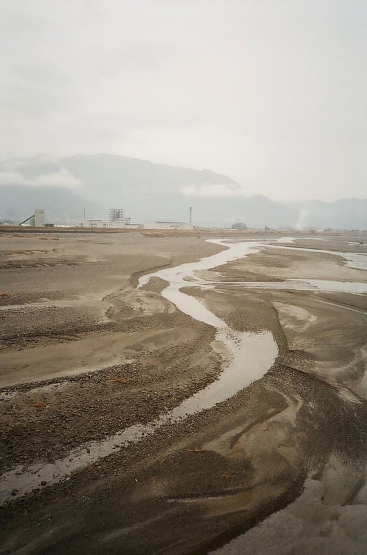 山梨県にある釜無川です。
冬の山に囲まれている中で川の水が一筋流れ周りにある砂利が濡れて星粒のように光ってい流れているように見えました。