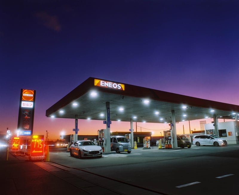 夕闇に包まれるガソリンスタンド。ネオンの光がぼんやりと灯り。